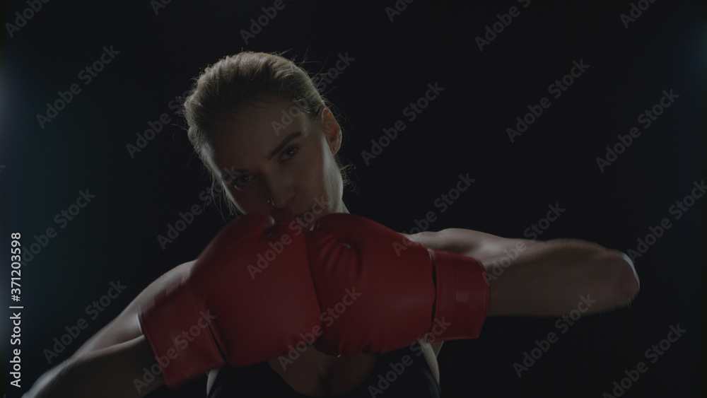 Woman fighter kicking hands in red boxing gloves. Portrait of woman boxer