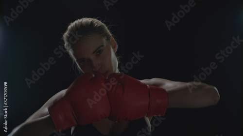 Woman fighter kicking hands in red boxing gloves. Portrait of woman boxer © stockbusters