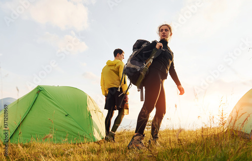 Fototapeta Naklejka Na Ścianę i Meble -  Couple having a walk outdoors near green tent. Conception of traveling