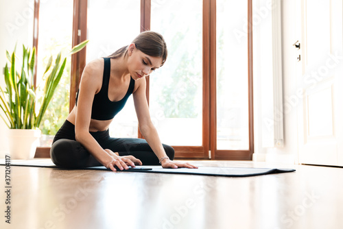 Fit young woman using cellphone while doing exercise