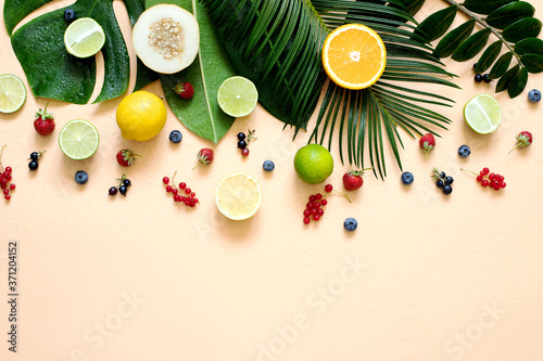 Wet Tropical leaves with fruit and berries on a beige background in pastel colors.