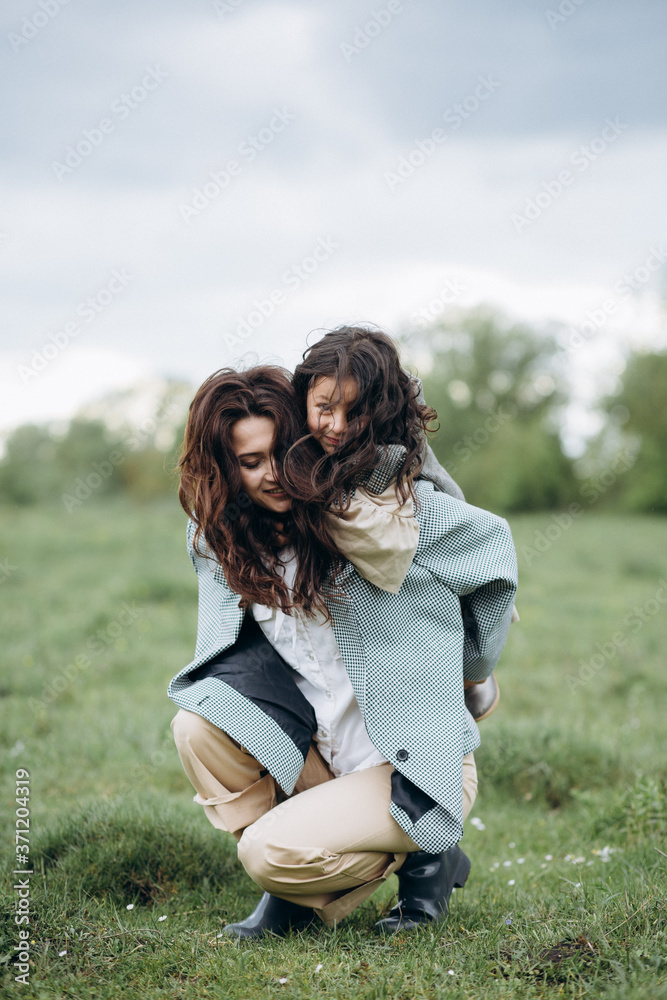 Portrait of hipster mother with daughter in her arms in the field. The family is having fun together Portrait of hipster mother with daughter in her arms in the field. The family is having fun together