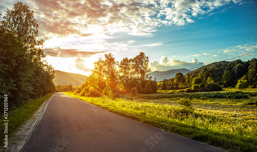 Bieszczady Poland. Road in the mountains at sunset in summer. Sun rays at sunset over the road.