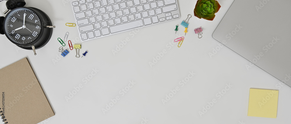 Flat lay of modern workspace with laptop, keyboard, notebook, clock and office supplies. Top view. Flat lay of modern workspace with laptop, keyboard, notebook, clock and office supplies. Top view.