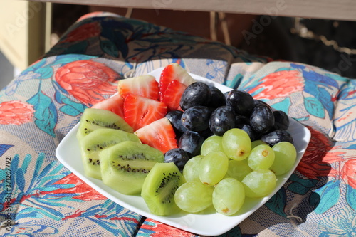 black seedless grapes with white seedless grapes with strawberries and kiwi fruit salad on a colorful floral background