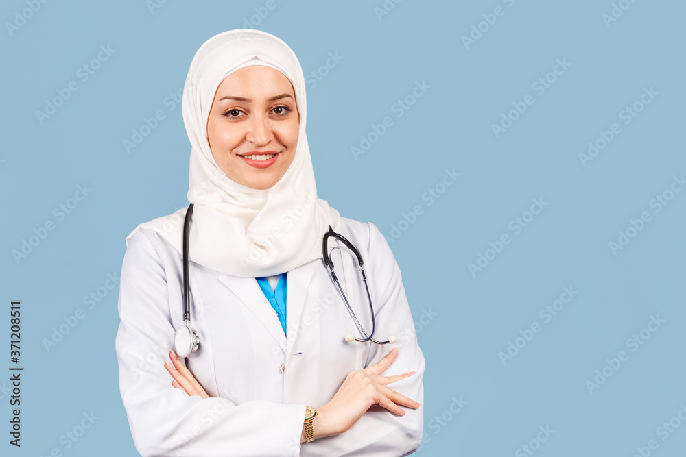 Portrait of a friendly, Muslim doctor or nurse woman in hijab with a stethoscope in a white coat. on a blue background. Portrait of a friendly, Muslim doctor or nurse woman in hijab with a stethoscope in a white coat. on a blue background.