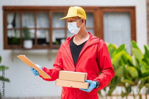 deliverdelivery man Wearing blue gloves in red cloth holding cardboard boxesy man Wearing blue gloves in red cloth holding cardboard boxes photo