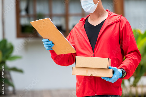 deliverdelivery man Wearing blue gloves in red cloth holding cardboard boxesy man Wearing blue gloves in red cloth holding cardboard boxes photo