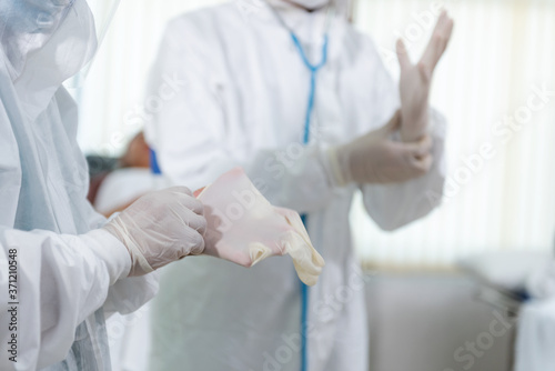 Obraz na płótnie Doctors put on protective gloves and suit mask before Patient treatment in hospital patient in the control area