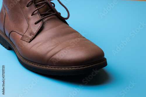 Brown leather man shoe on blue background with copy space