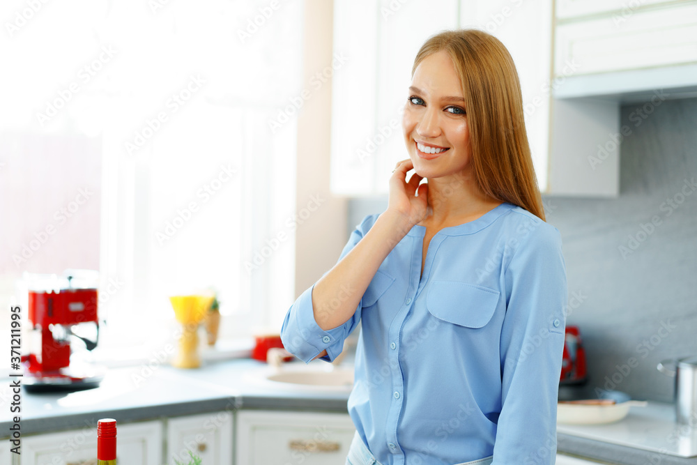 Blonde woman standing in kitchen and cooking Blonde woman standing in kitchen and cooking