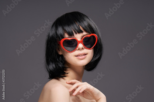 Woman wearing sunglasses in the shape of a heart bared shoulders short hairstyle close-up cropped view smile