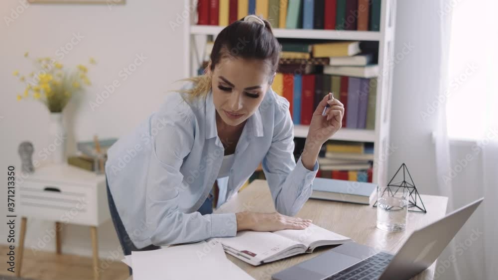Young woman wears headset conference calling on laptop talks with online teacher studying, working from home. Lady student e learning using computer webcam chat makes notes. Distance education concept Young woman wears headset conference calling on laptop talks with online teacher studying, working from home. Lady student e learning using computer webcam chat makes notes. Distance education concept