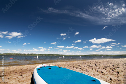 A paddle board lays on the sandy beach of Skeleton lake Alberta Canada.