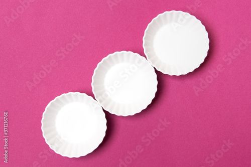three empty white plate on purple colored paper background