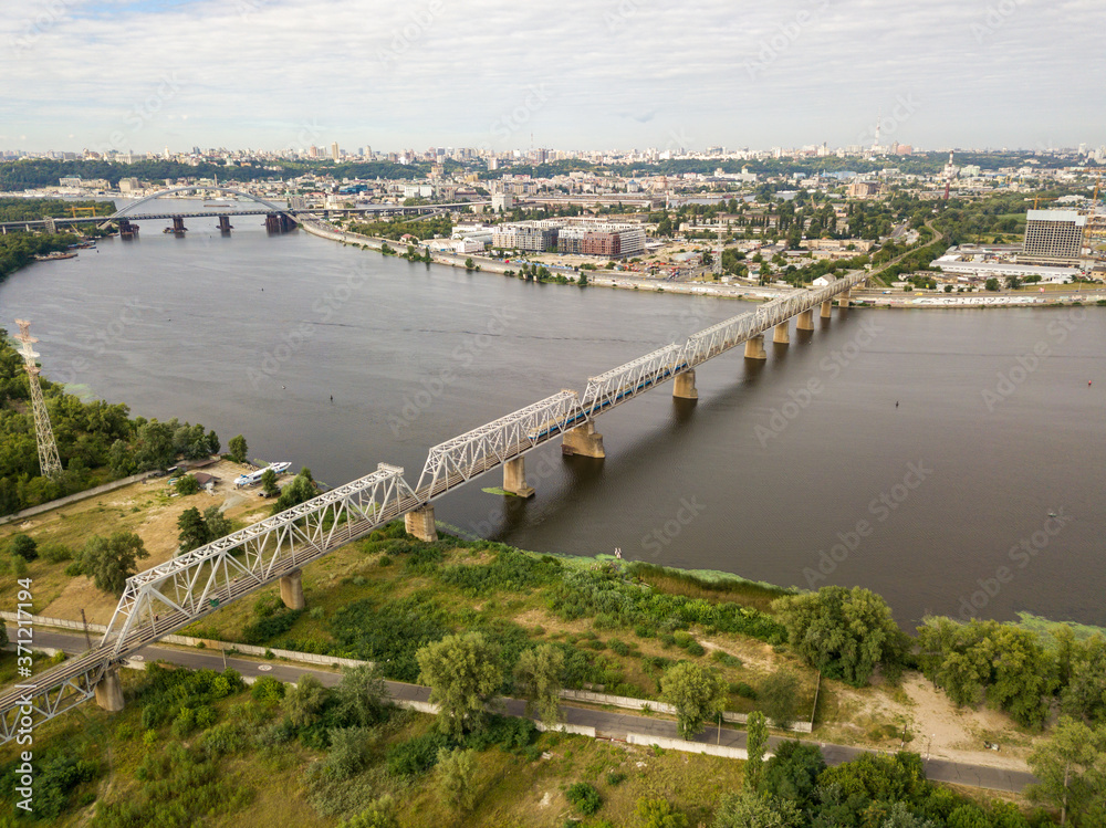 Aerial drone view, The train travels along the railway bridge across the river.