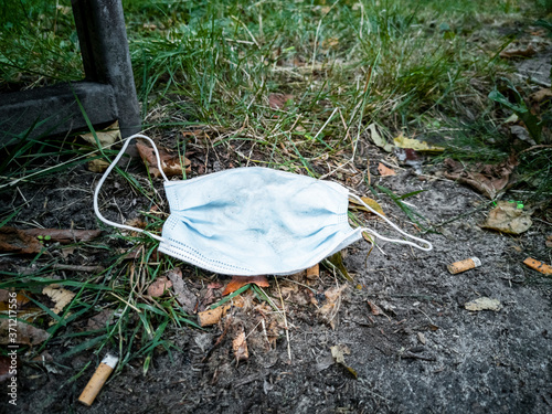 Surgical masks and cigarette butts in nature. Corona virus pollution.