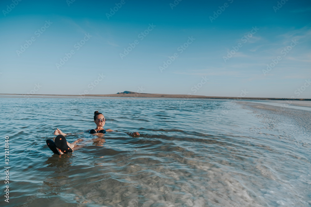 The woman swims in the dead sea. Lie on the water.