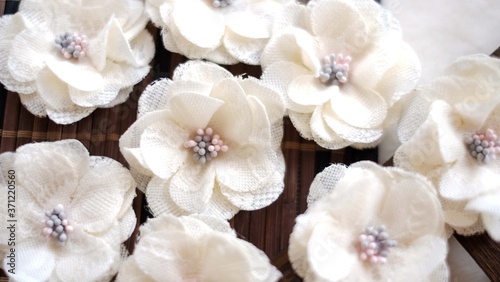Artificial handmade flowers made out of beautiful lace fabric texture in broken white color