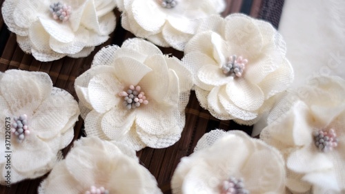 Artificial handmade flowers made out of beautiful lace fabric texture in broken white color