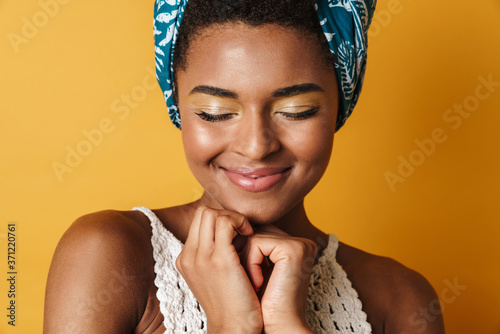 Image of pleased african american woman smiling with eyes closed