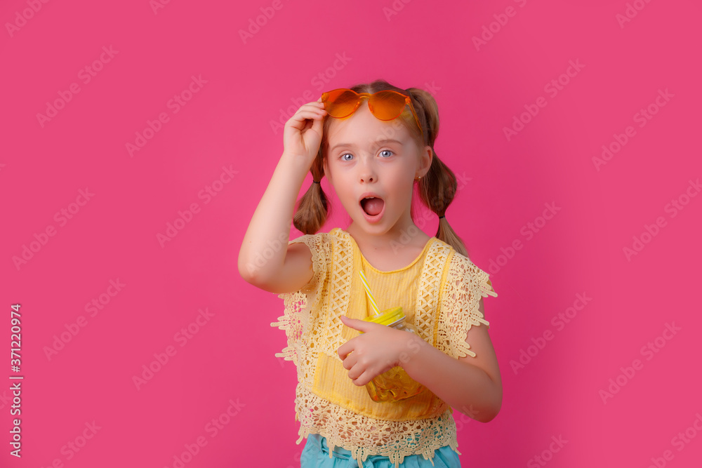 a little girl in sunglasses with a cocktail on a pink background