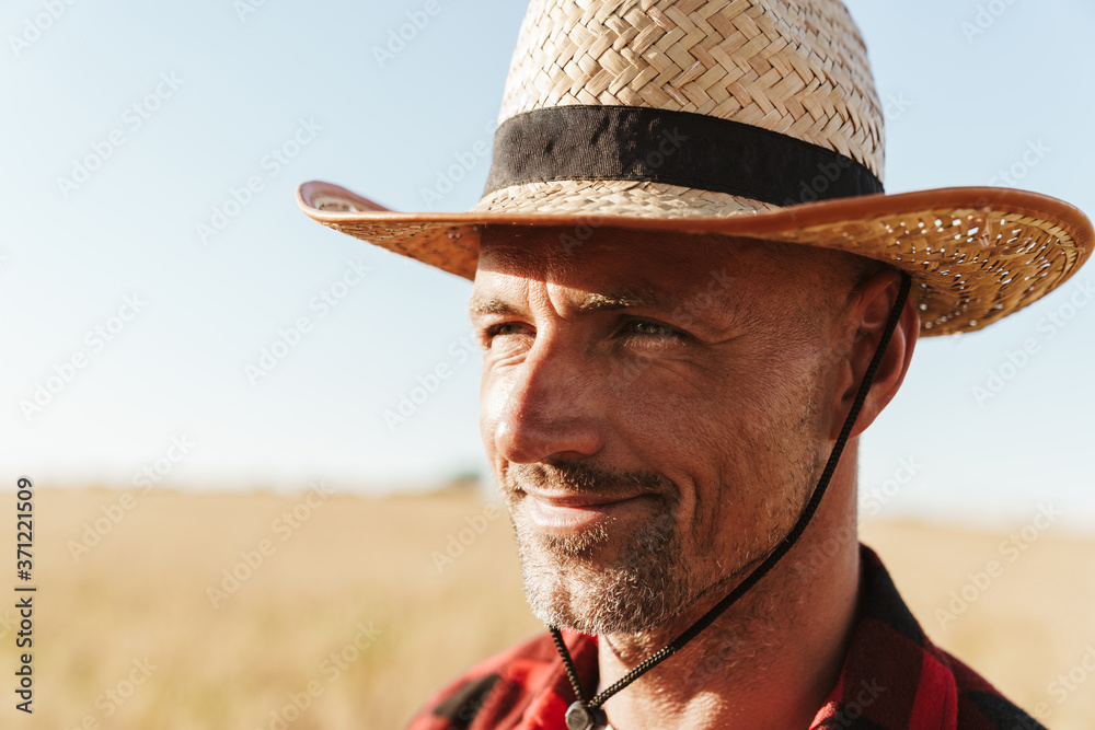 Image of pleased man looking aside while standing at cereal field