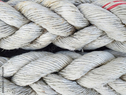 Background of braided old thick ropes. Sturdy fishing ropes to tie up the boat. Close up. Detail of a used Trawler white fishing net.
