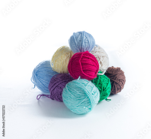 Pyramid of colorful yarn balls on a white surface and white background. Pile of knitting or crochet supplies, ready to be made into a warm clothing item.