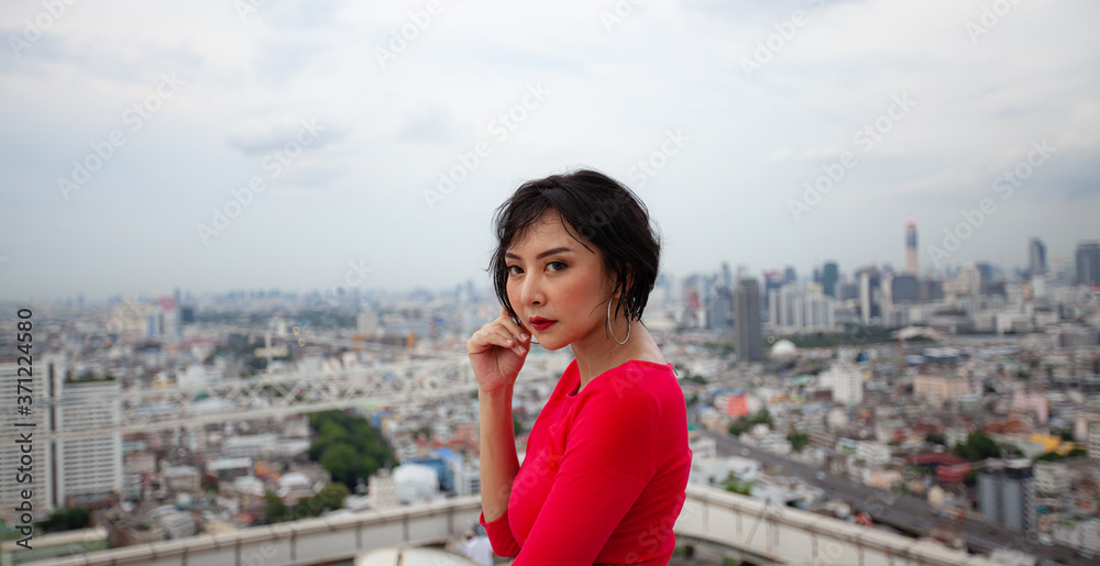Portrait of a businesswoman in a red dress is watching the top of the office building. real people real body concept Portrait of a businesswoman in a red dress is watching the top of the office building. real people real body concept