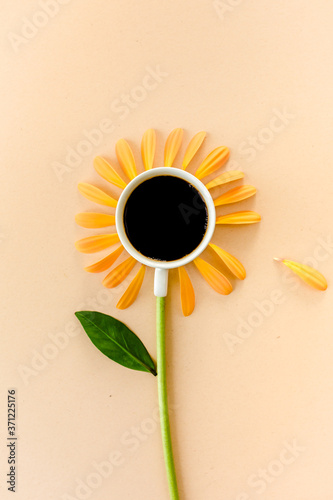 Photographie Cup of coffee and flower petals on a beige background
