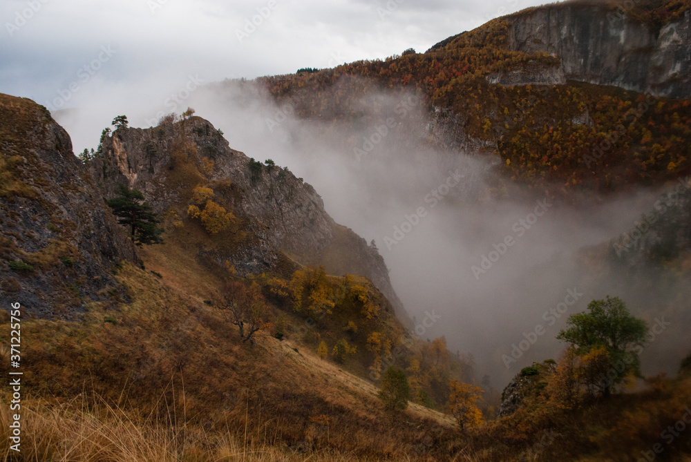 Fog in valley between mountains in autumn