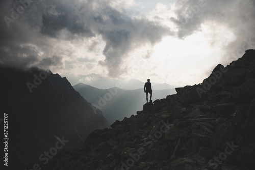 Man in mountains, silhouette of young hiker, sunset sky and hills in background--