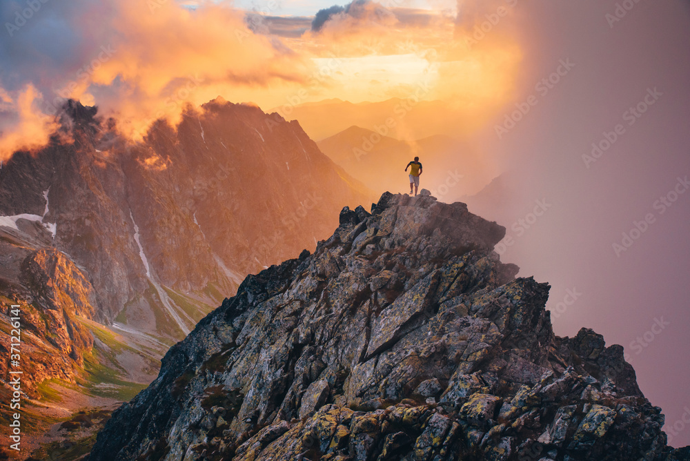 Naklejka premium Alone runner on the top of the hill. Sunset scenery in mountains.