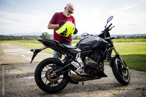 A middle-aged man enjoys with his motorcycle © romul014