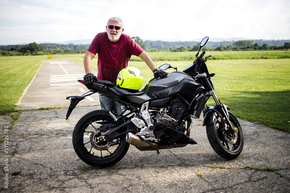 A middle-aged man enjoys with his motorcycle A middle-aged man enjoys with his motorcycle