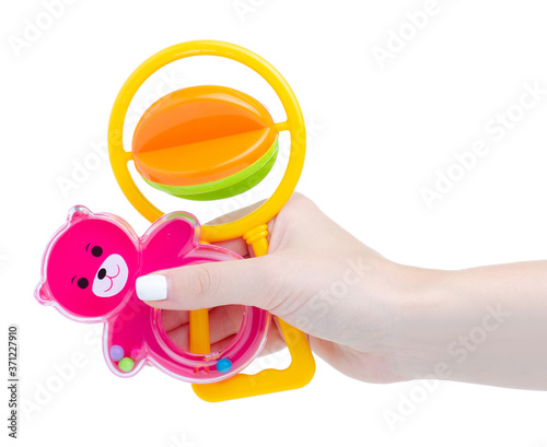 Baby pink and yellow rattle in hand on white background isolation photo