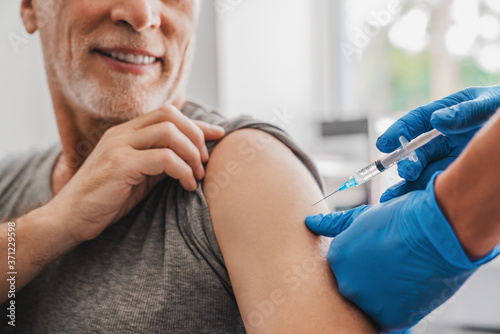 Doctor making injection to senior patient in clinic photo