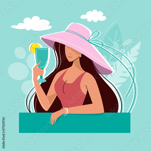 A young summer girl in a hat and in a swimsuit is holding a glass with a cocktail. Summer time, vacation