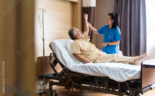 Asian physiotherapist nurse helping elderly men physical rehabilitation on bed at hospital