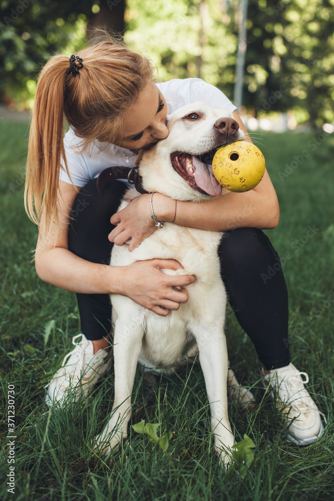 Close up photo of a blonde girl and her golden retriever playing with a ball on the grass Close up photo of a blonde girl and her golden retriever playing with a ball on the grass