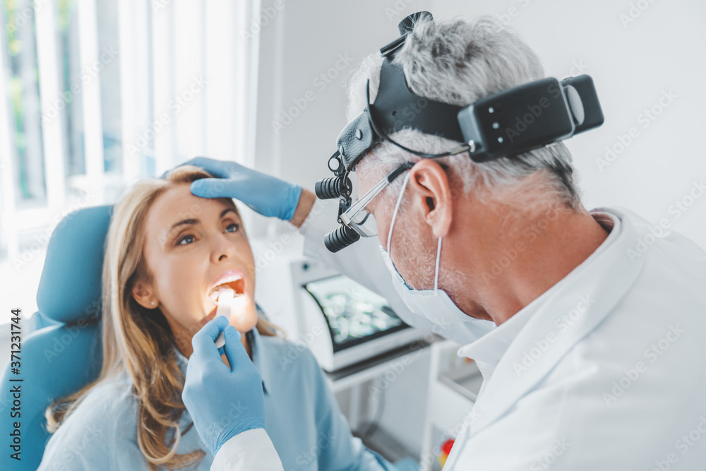 Mature doctor checking woman throat with medical stick Mature doctor checking woman throat with medical stick
