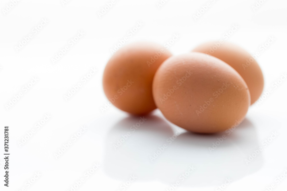 Three large brown chicken eggs on a white background with reflection. Three large brown chicken eggs on a white background with reflection.