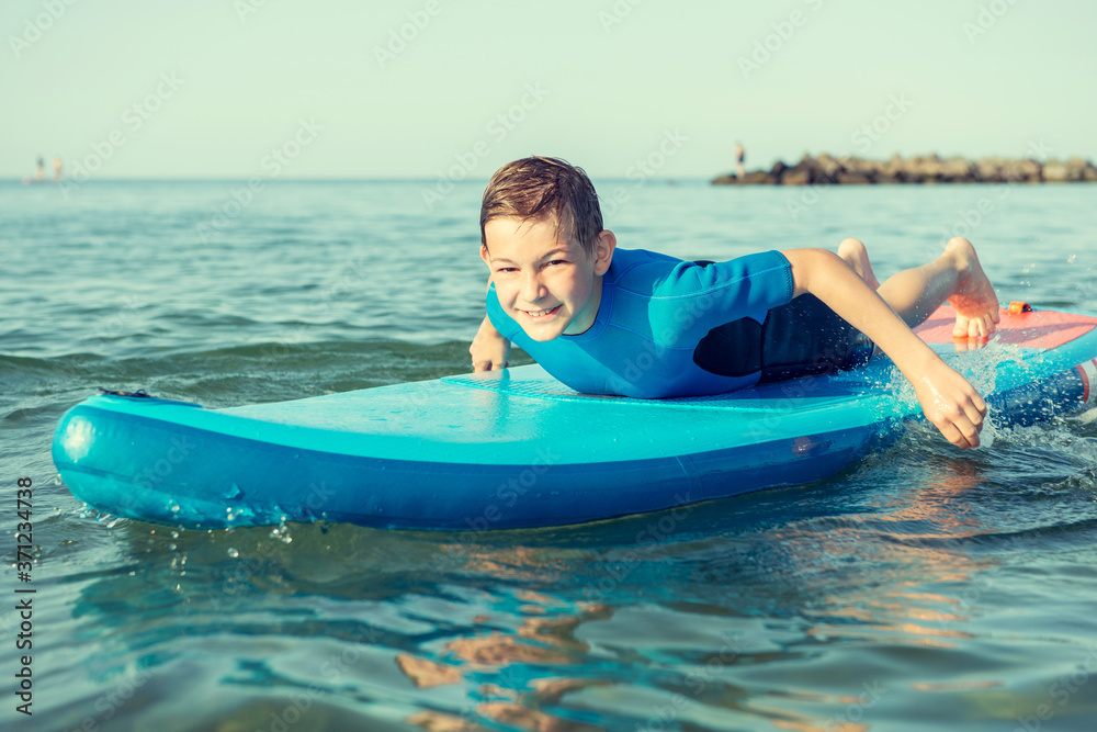 Happy teen child boy having fun and making sport on sup board in Baltic sea