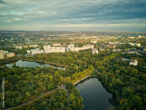 Aerial view of a lake in a park with autumn trees. Kishinev, Moldova. Epic aerial flight over water. Colorful autumn trees in the daytime.