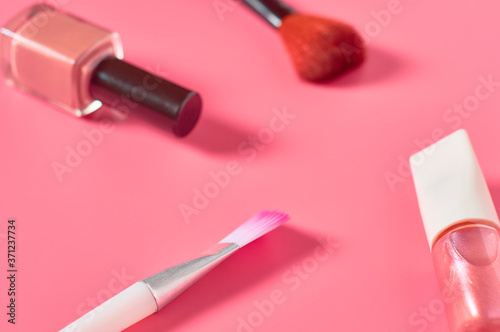 Bottles of luxury nail polish and brushes for powder on pink background. Beauty and fashion concept
