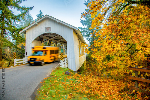 School bus emerging from Hannah covered bridge near Sio, Oregon, blurred to show motion