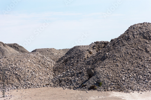 Industrial background with pile of gravel in front of the sky. Extraction of gravel. Construction of roads. Piles of gravel on construction site. Morning. Beautiful light.