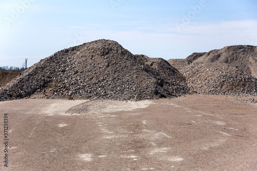 Industrial background with pile of gravel in front of the sky. Extraction of gravel. Construction of roads. Piles of gravel on construction site. Morning. Beautiful light.