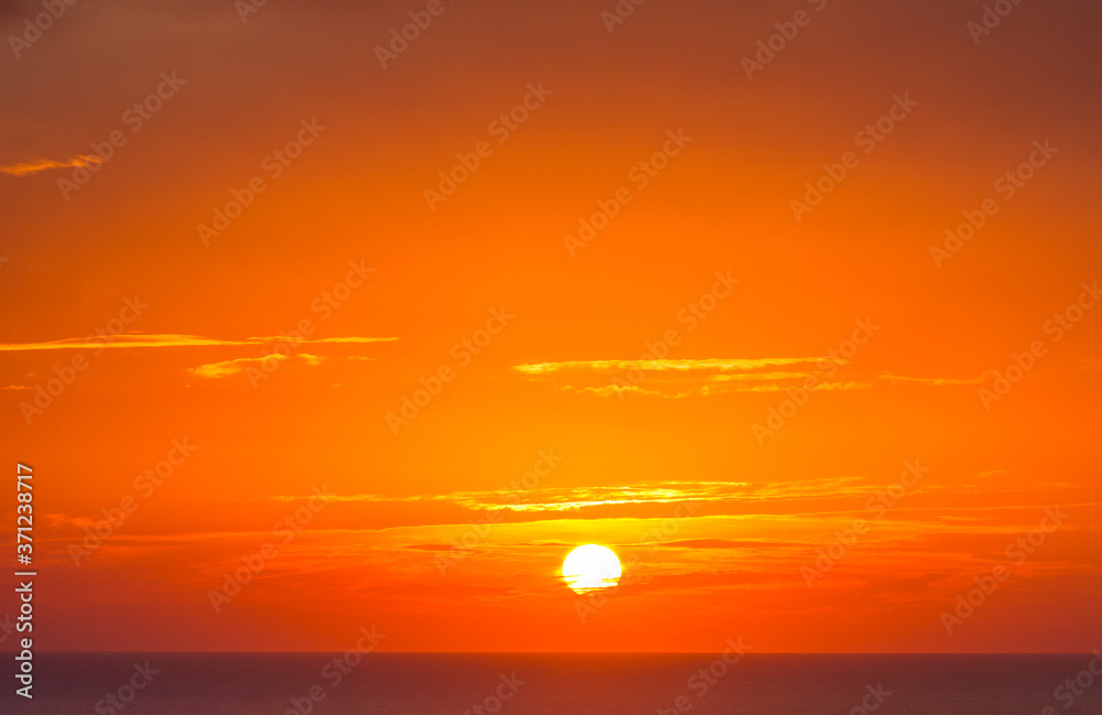 Brilliant orange-red clouds reflected into the ocean in a beautiful sunset